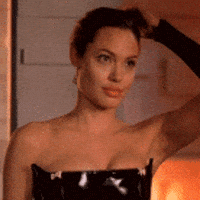 Movie gif. Angelina Jolie wears a black patent leather bustier as Jane in Mr. and Mrs. Smith. She unclips her hair and shakes it out slowly before looking up seductively.