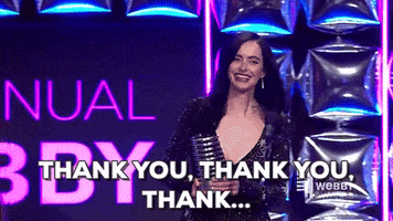 Celebrity gif. Krysten Ritter as Jessica Jones wears a low cut, glittery black gown. She rushes towards a microphone on stage with an award in her hand. Text reads, "Thank you, Thank you, Thank..."