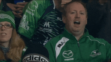 Sports gif. An Irish rugby fan is sitting in the stands and is upset as he yells, "Fuck!"