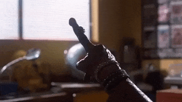 Movie gif. ET from ET wears multiple bracelets on his alien arm as he points a finger towards a window. 