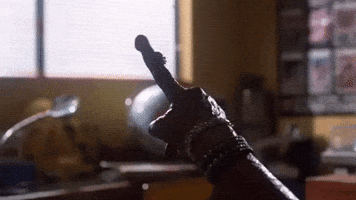 Movie gif. ET from ET wears multiple bracelets on his alien arm as he points a finger towards a window. 