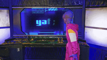 Video gif. A purple alien wearing a pink jumpsuit looking at a screen that says "yes," turns around and pumps its arm.