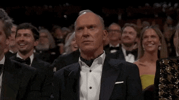 Oscars 2024 GIF. Michael Keaton, seated at the Oscars, dramatically stonewalls, judgmentally unamused.