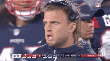 Sports gif. Steve Belichick makes funny faces, sticking his tongue out, snarling, frowning and grimacing from the sidelines on a New England versus Tampa Bay game.