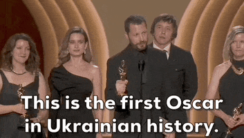 Oscars 2024 GIF. Mstyslav Chernov, director of 20 Days in Mariupol, holds his award out in front of him and he informs the crowd, "This is the first Oscar in Ukrainian history." 