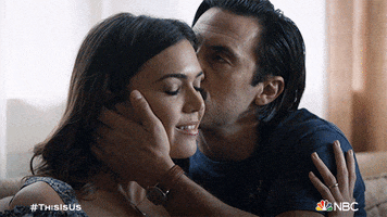 TV gif. Mandy Moore as Rebecca sitting with Milo Ventimiglia as Jack on This Is Us, as he gives her a loving kiss on the cheek.