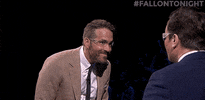 The Tonight Show gif. Jimmy Fallon spits a bunch of water into Ryan Reynolds's face. Ryan leans his head back in disgust, stepping away from jimmy.