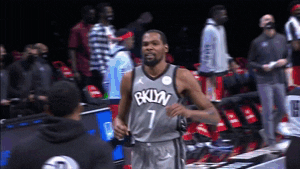 Sports gif. Kevin Durant wears a Brooklyn Nets jersey as he walks past a bunch of people and gives them high fives.