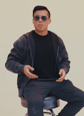 Video gif. A man sitting on a stool wearing blue Aviator sunglasses, holds up one hand, then the other, gesturing two options.