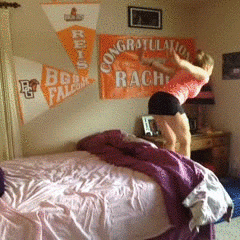 Video gif. A woman bounces backward into bed, tucking herself in with a backflip. Another woman attempts the same, but loses control, bouncing out of the bed and face-planting onto the floor.