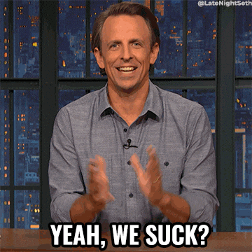 Late Night gif. Seth Meyers claps sarcastically, then shrugs as he says, "Yeah, we suck?"
