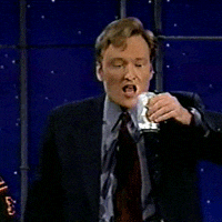 TV gif. Conan O'Brien holds a can of beer up and pours it into his open mouth, but most of the contents spill over down his face and clothes.