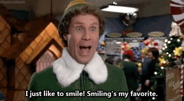 Movie gif. Will Ferrell as Buddy in "Elf" stands in front of a store's Christmas display, smiles earnestly as he says "I just like to smile! Smiling's my favorite," which appears as text.