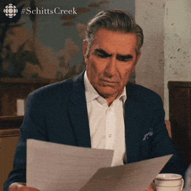 Gif of Jonny Rose character from Shitt's Creek looking at papers with caption, What am I looking at?