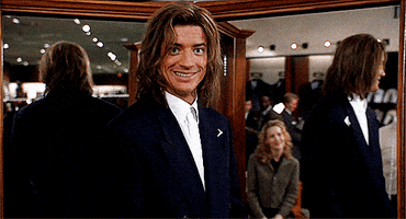 Movie gif. Brendan Fraser as George in George of the Jungle. He's trying on suits in a store and he stands in the middle of multiple mirrors. He gives us a grin that stretches from ear to ear.