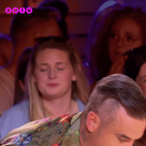Reality TV gif. Robbie WIlliams on the X Factor leans forward as he enunciates each word that appears one at a time. Text, "Thank god you arrived!"