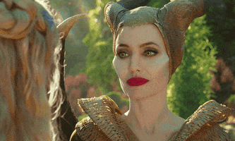 Disney gif. Angelina Jolie as Maleficent pouts and tilts her head to the side as if considering something.