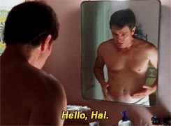 TV gif. Bryan Cranston as Hal on Malcolm in the Middle stands in front of a mirror with his shirt off. He grabs his gut and shales and says, “Hello, Hal.”