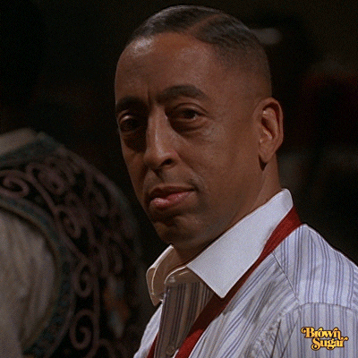 Celebrity gif. Gregory Hines looking suave in a striped, collared shirt with his hair slicked to one side. He winks, then grins and begins chuckling.
