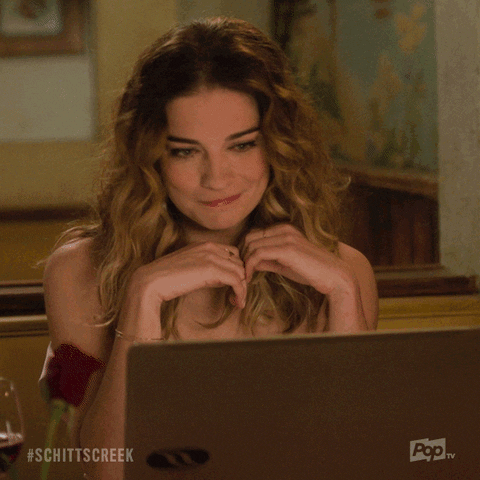 Alexis from Schitt's Creek TV Shows smiles and says 'I'm just happy to see your face' to a laptop. A gif.