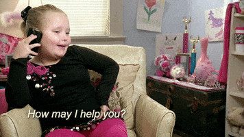 Reality TV gif. Honey Boo Boo on the phone, sitting in a sofa chair, saying "how may I help you?" 