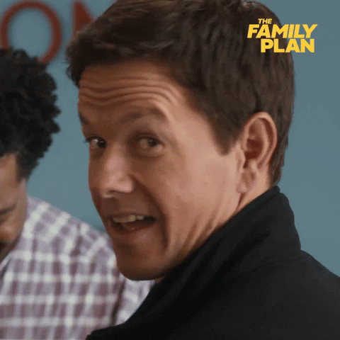 Movie gif. Mark Wahlberg as Dale in "The Family Plan" turns to look back over his shoulder at us with a sarcastic smirk on his face and gives a quick wink. 