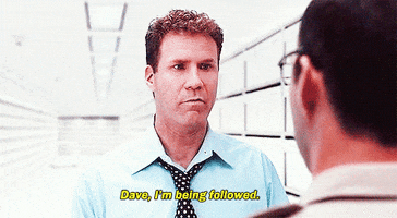 Movie gif. Will Ferrell as Harold Crick in Stranger Than Fiction stiffly whispers to a coworker "Dave, I'm being followed," who glances puzzledly around the very empty room.