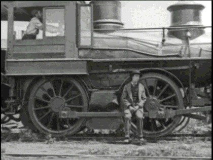 Black and white gif of Buster Keaton sitting morosely on the strut between train wheels going up and down as the wheels turn. 