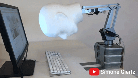 Gif of a manequin head on a robotic arm smooshing itself repeatedly on a keyboard