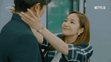 TV gif. Park Min-Young as Seong Deok-mi in Her Private Life grabs Kim Jae-Wook as Ryan by the neck and kisses his cheek while he calmly gazes down at her.