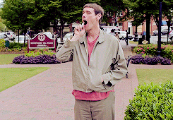 Movie gif. Jim Carrey as Lloyd Christmas in Dumb and Dumber stands in a park trying to pray mouth spray in his mouth, but the nozzle is turned the wrong way and just spritzing into the air, not his mouth. Lloyd is then in a gymnasium at a dance and falls off his clothes to reveal a superhero costume.