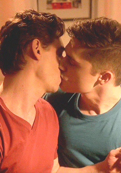 Video gif. Two men are in the middle of a lovely kiss and they both begin to smile as the kiss lingers on.