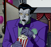 Cartoon gif. The Joker from the animated Batman series looks engrossed ahead as he holds a bucket of popcorn and slowly chews. 