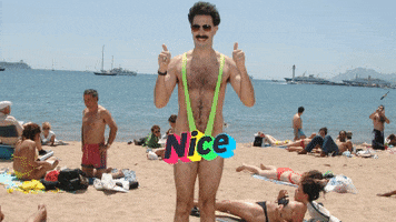 Movie gif. A smiling Sacha Baron Cohen as Borat stands on a crowded beach, wearing nothing but a neon green mankini that stretches from his crotch to his shoulders. He gives two thumbs up. Text, “Nice.”