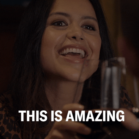 TV gif. Alyssa Diaz as Angela Lopez on The Rookie clings her wine glasses with another to toast. She has a big smile on her face as she says, “This is amazing.” Then, she sips her wine. 