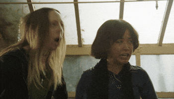 TV gif. Maya Erskine as Maya Ishii-Peters and Anna Konkle as Anna Kone in PEN15 violently gyrate and rock their heads, their eyes rolling back.
