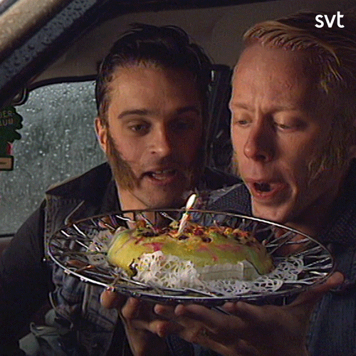 TV gif. Peter Settman and Fredde Granberg as Ronny and Ragge. They're sitting in a car and are holding a plate with a cake and a burning candle. They stare at the cake before blowing it out and squirming in glee.  