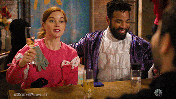 TV gif. Two couples from Zoey's Extraordinary Playlist raise flutes of champagne for a cheerful toast.  