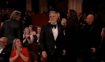Oscars 2024 GIF. Brad Booker walks down the red carpet towards the stage to accept his award for War is Over. He's totally amped and he looks into the camera, raising both fists in an air pump and gives us an enthusiastic growl.