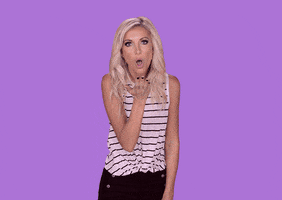 Celebrity gif. Red hearts bloom out towards us as Taylor Bisciotti blows kisses from the left, middle, and right.