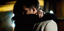 Video gif. A man and a woman hug passionately.