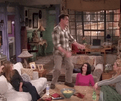 Friends gif. Matthew Perry as Chandler dancing awkwardly on a coffee table while Jennifer Aniston as Rachel, Courteney Cox as Monica, and Lisa Kudrow as Phoebe watch unamused.