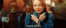 Movie gif. Lindsay Lohan as Hallie in The Parent Trap crosses her arms and her fingers as she smiles and says, "Good luck."