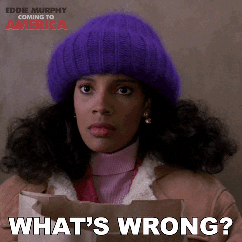 An animated gif video clip from the Eddie Murphy movie Coming to America. A young Black woman with a purple toque on and natural hair is holding a paper grocery bag and says "What's wrong?"