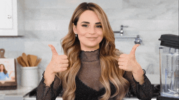 Celebrity gif. Rosanna Pansino is standing in a kitchen and she smiles with her lips closed. She gives us two thumbs up and looks pleased.