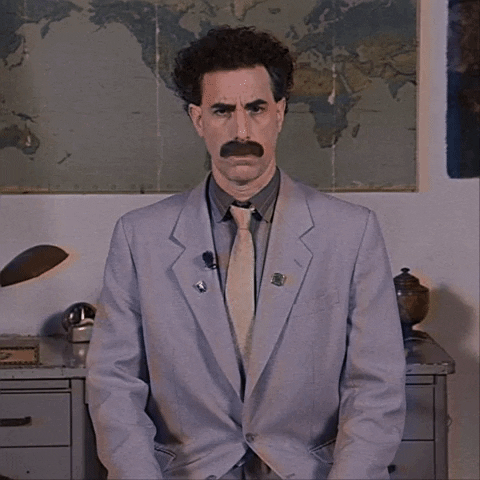 Movie gif. Poor-quality "VHS" footage of Borat staring straight at us and nodding.