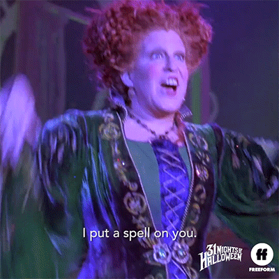 Halloween gif. Bette Midler as Winifred in Hocus Pocus shimmies and lowers her hands dramatically while singing “I put a spell on you.”
