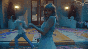 Music video gif. Taylor Swift fans herself off with her hand as chaos ensues in the background, from the music video for the song "Me."
