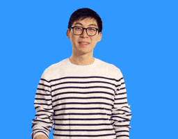 Video gif. A man in a striped shirt and glasses points at us and nods, making a hand heart over his chest.