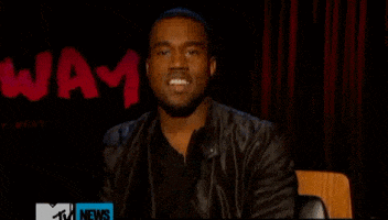 Celebrity gif. Kanye West lifts his shoulders up high and shrugs. He looks at us with a big grin. 